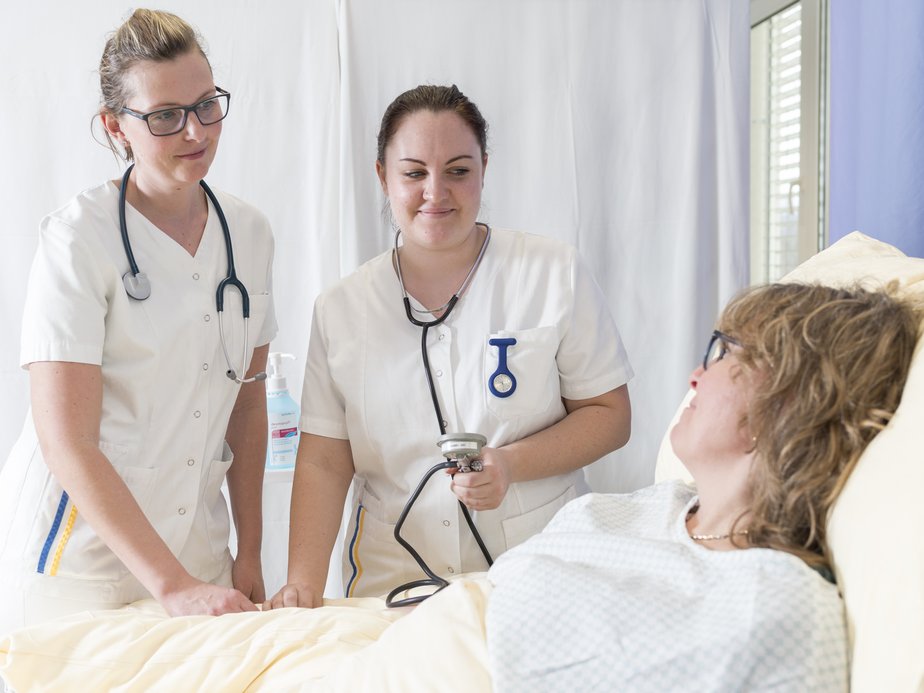 Zwei Pflegeassistentinnen und eine Patientin.