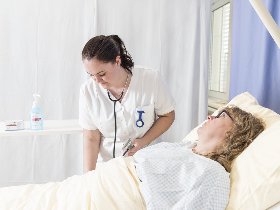Eine Pflegeassistentin steht neben einer Patientin.